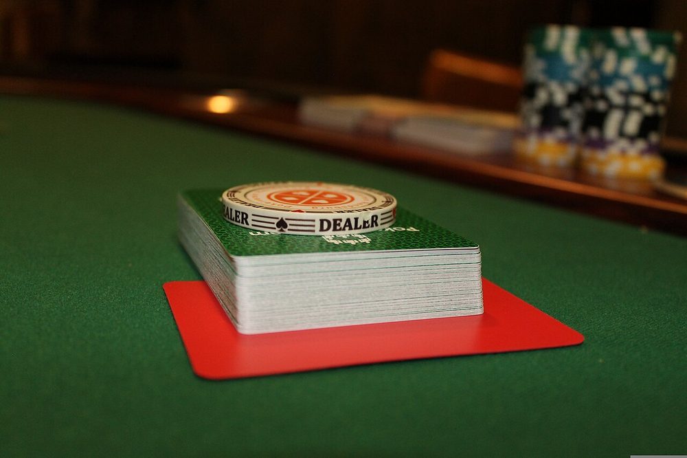 A deck of playing cards on a card table with chips behind